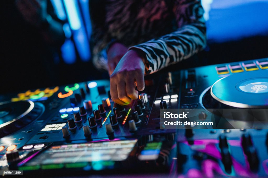 Close up of DJ hands controlling a music table in a night club.